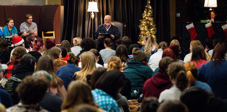 Susquehanna University President Jonathan Green sits in front of a large crowd of students dressed in pajamas.